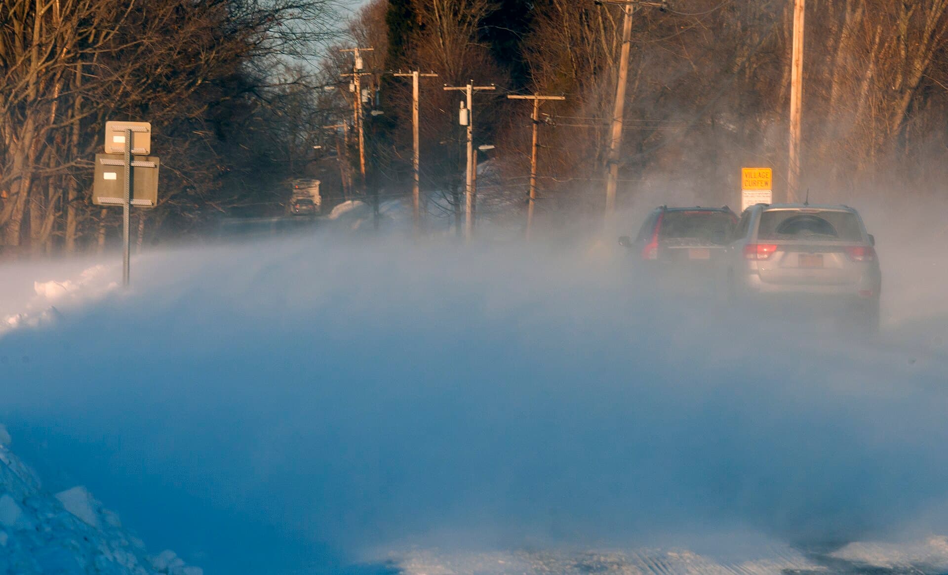 Cars driving through blowing snow on a highway